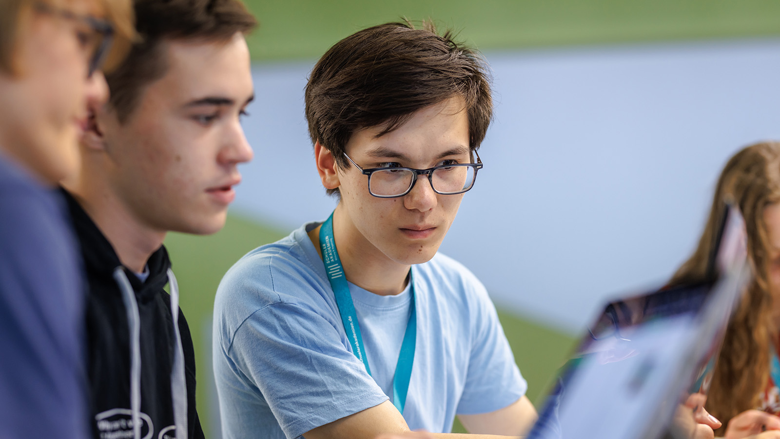 Drei Jugendliche schauen konzentriert gemeinsam auf ein Dokument.