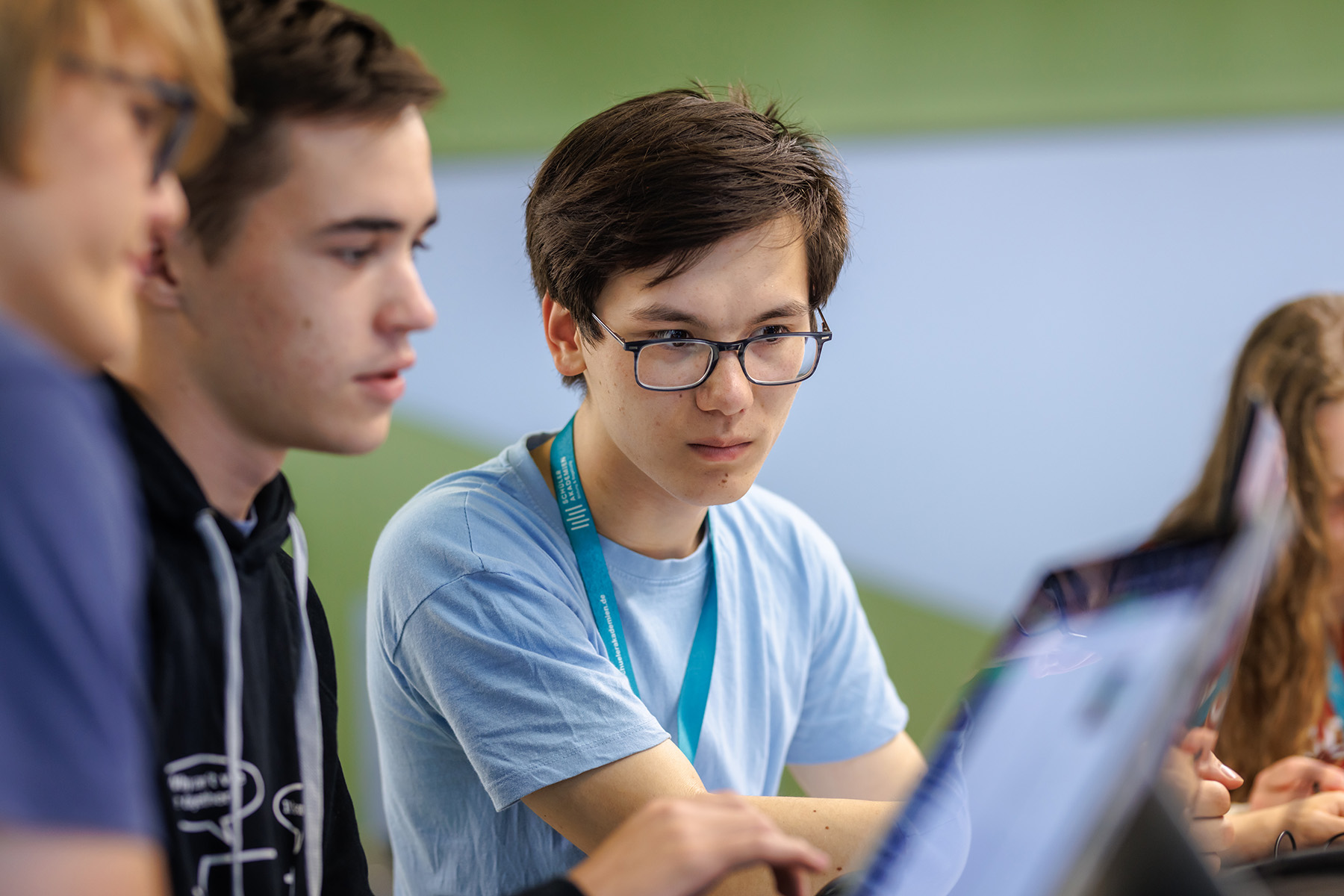 Drei Jugendliche schauen konzentriert gemeinsam auf ein Dokument.