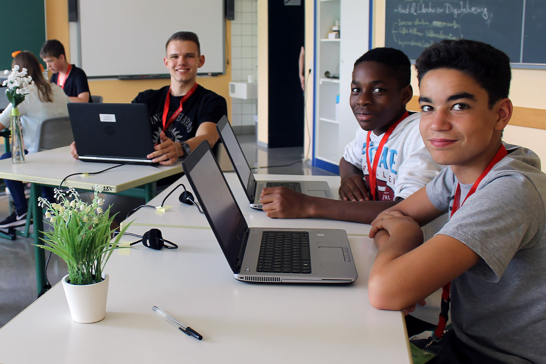 Mehrere Jugendliche sitzen in einem Klassenraum und arbeiten an Laptops.