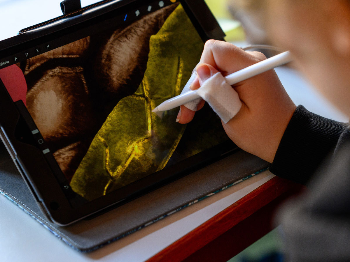 Eine Hand zeigt mit einem Stift auf ein Tablet.